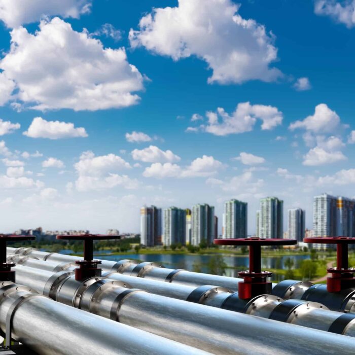 Industrial,Pipelines,Overlooking,A,Modern,Cityscape,Under,Blue,Sky